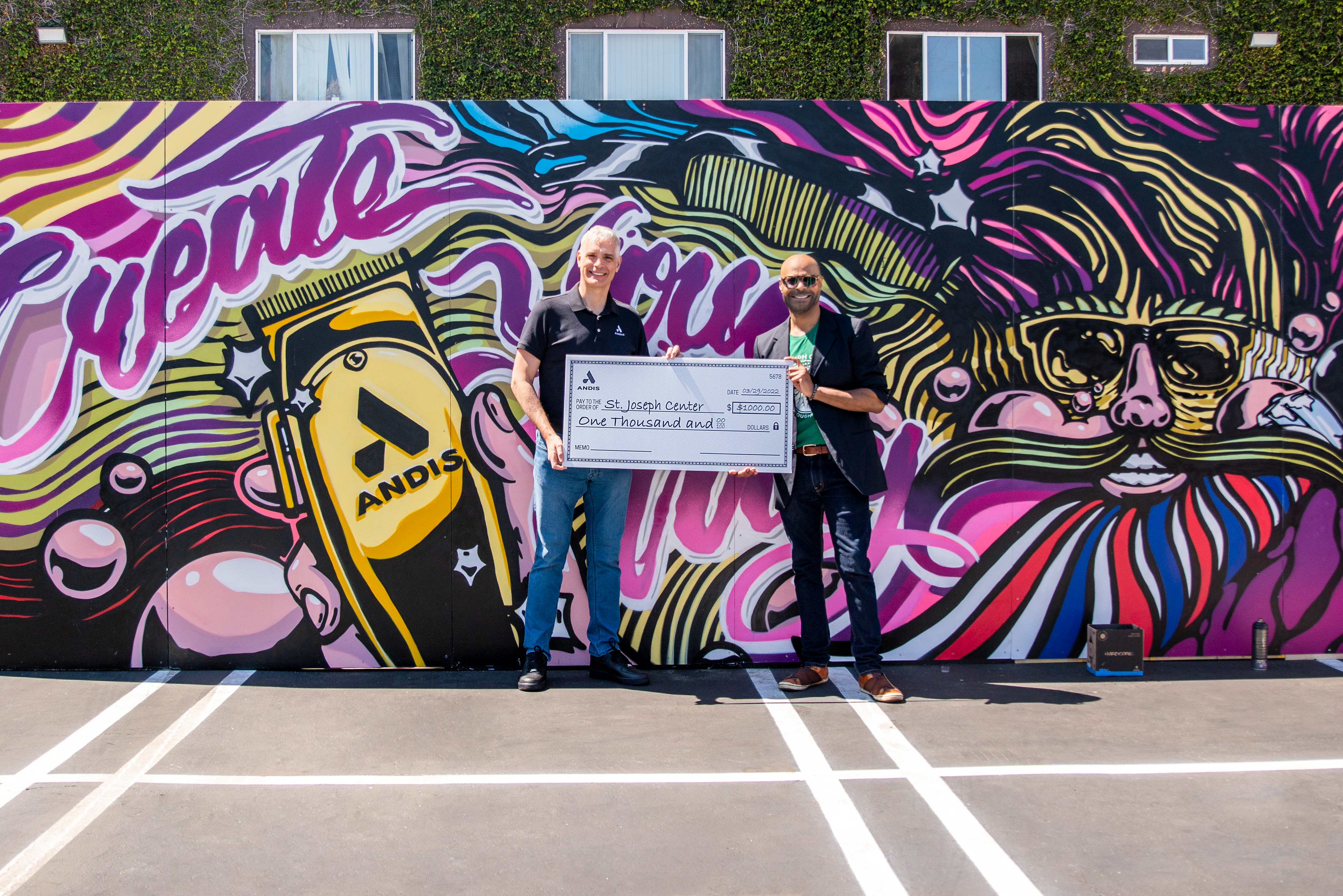 Brighter Community Venice Beach two men standing in front of mural holding large check