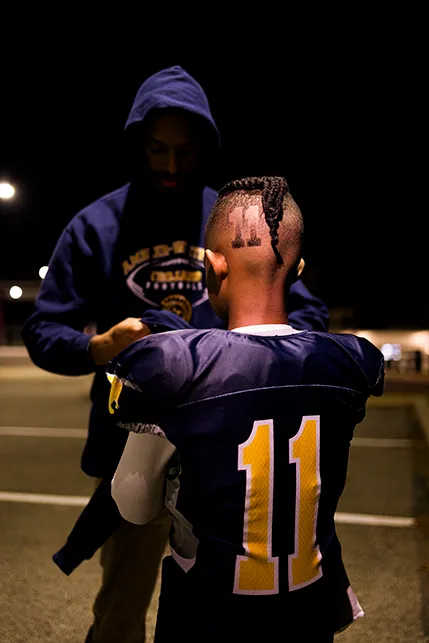 Man facing child, child has the number 11 shaved into his head