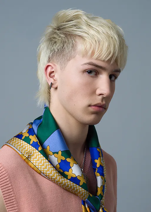 Blonde male model poses with fashionable Wave Fushion Mullet hairstyle