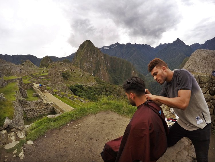 Julien Howard a.k.a. Velo Barber cutting a person's hair on a mountain top in Peru