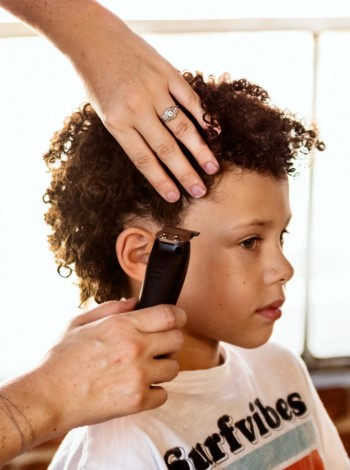 Large image of boy with curly brown hair getting hair cut