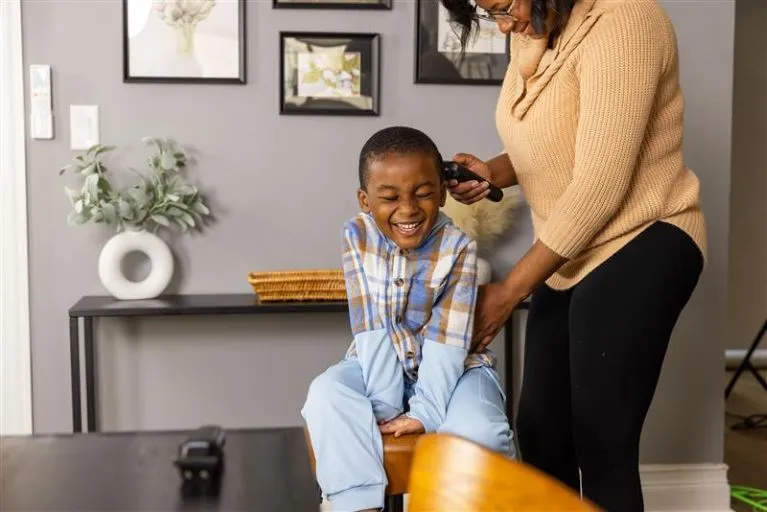 Boy getting hair cut by mother at home.