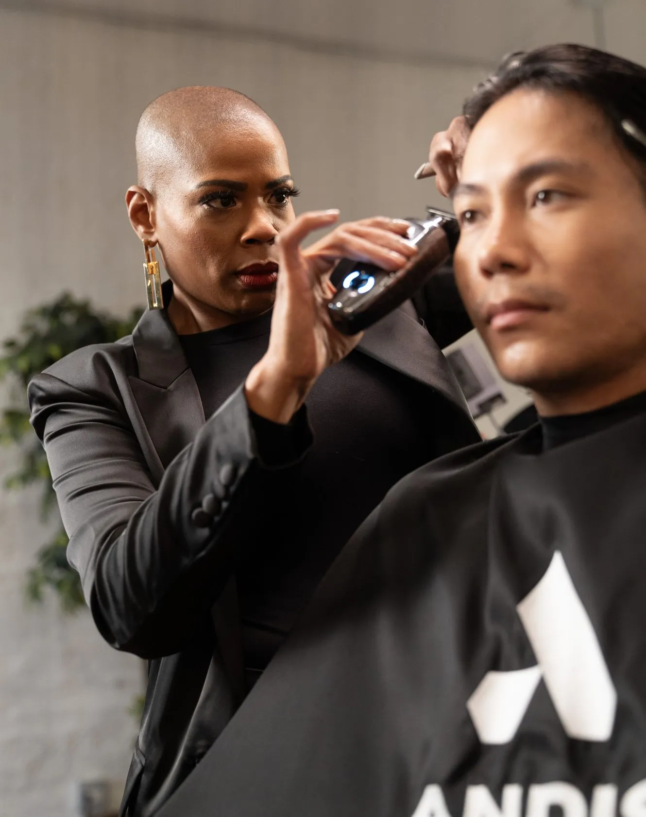 Woman clipping man's hair with Andis clipper.