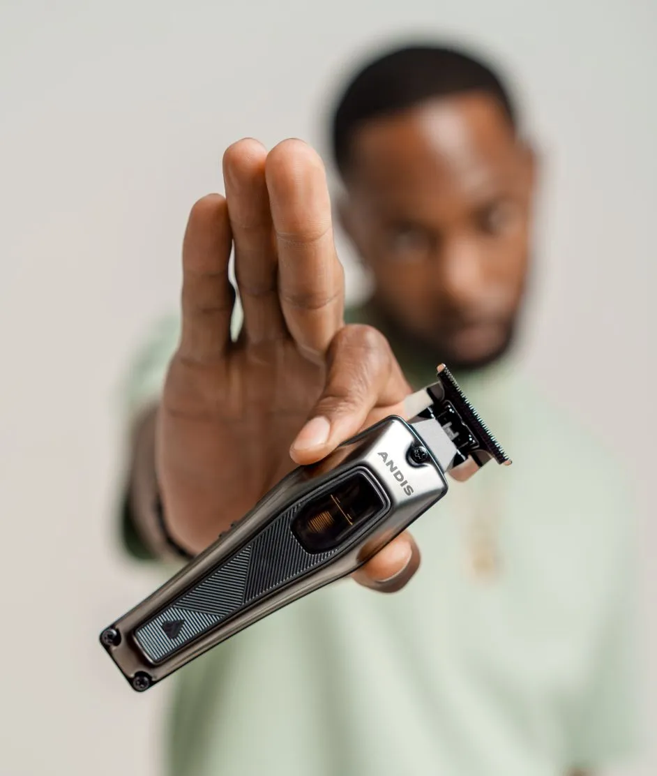 Blurred man holding a crisp Andis Recon clipper.