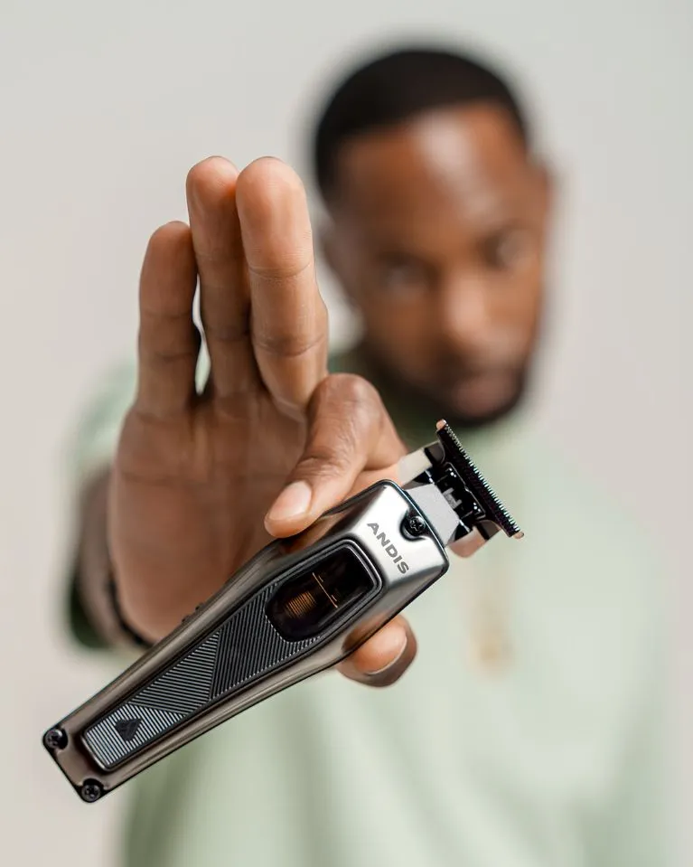 Blurred man holding a crisp Andis Recon clipper.